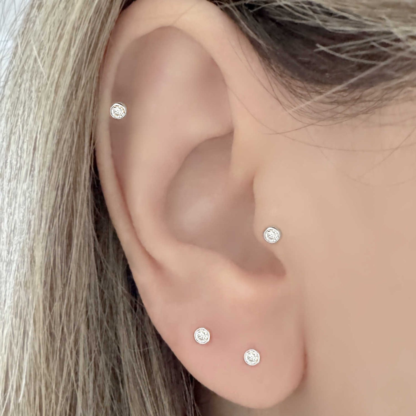 Woman Wearing Lab Grown Diamond and White Gold Earrings in Helix, Tragus and Lobe Piercings