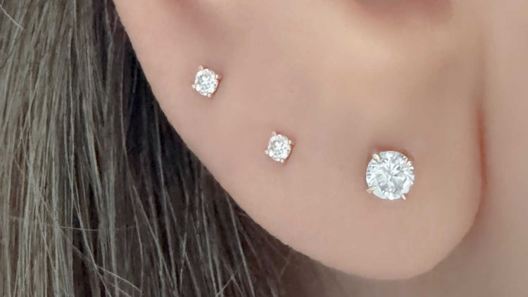 Woman wearing three flat back lab grown diamond stud earrings