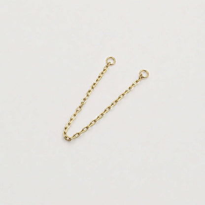 A 14k yellow gold cable chain double piercing earring charm with two circular jump ring ends, photographed on a plain light background.