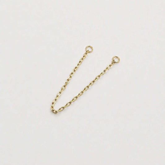 A 14k yellow gold cable chain double piercing earring charm with two circular jump ring ends, photographed on a plain light background.