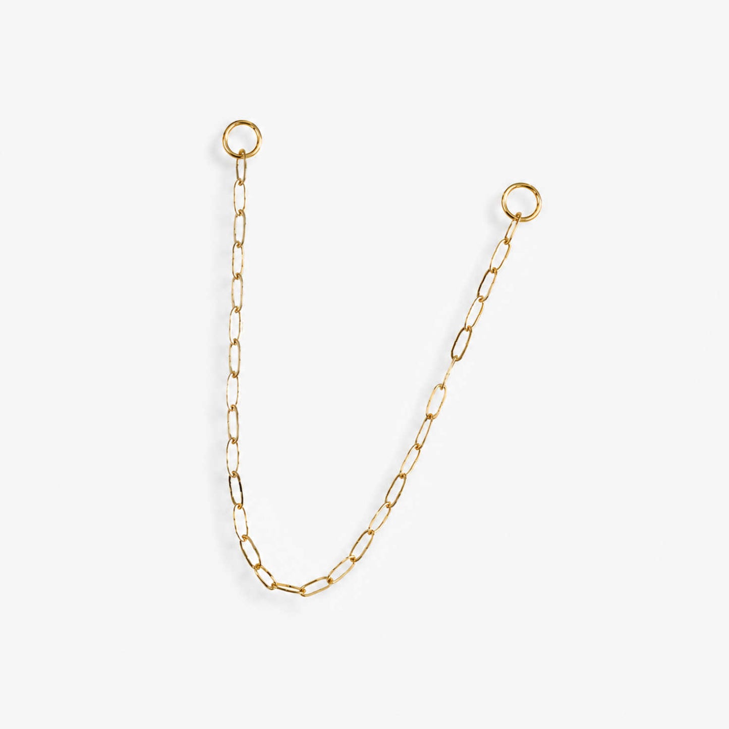 A delicate 14k yellow gold paperclip chain earring charm with two circular jump ring ends, displayed on a clean, light off-white background.