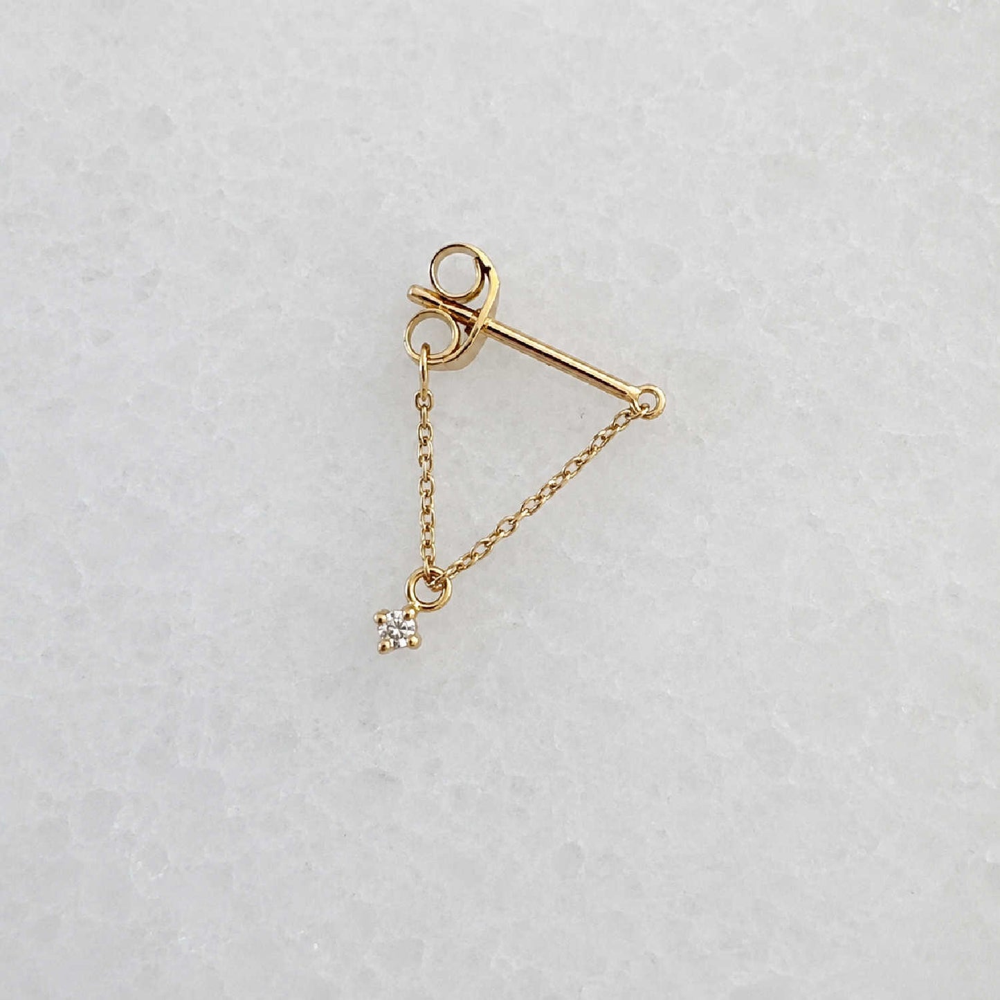Side view of a delicate 14k gold front back chain earring with a floating diamond charm