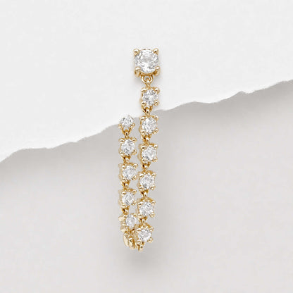 A 14k gold tennis style flat back dangle earring with multiple round-cut diamonds, photographed against a white background with a torn-paper style divider.