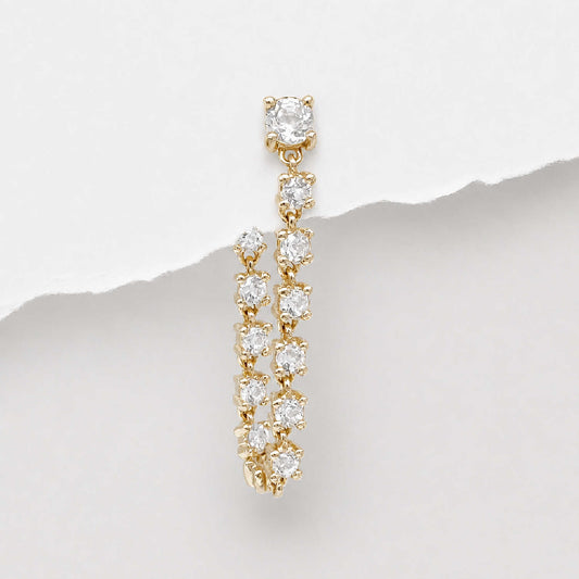 A 14k gold tennis style flat back dangle earring with multiple round-cut diamonds, photographed against a white background with a torn-paper style divider.