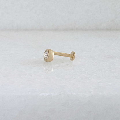 Side view of a single 14k solid gold stud flat back earring with a bezel-set diamond gemstone, shown on a light gray background.