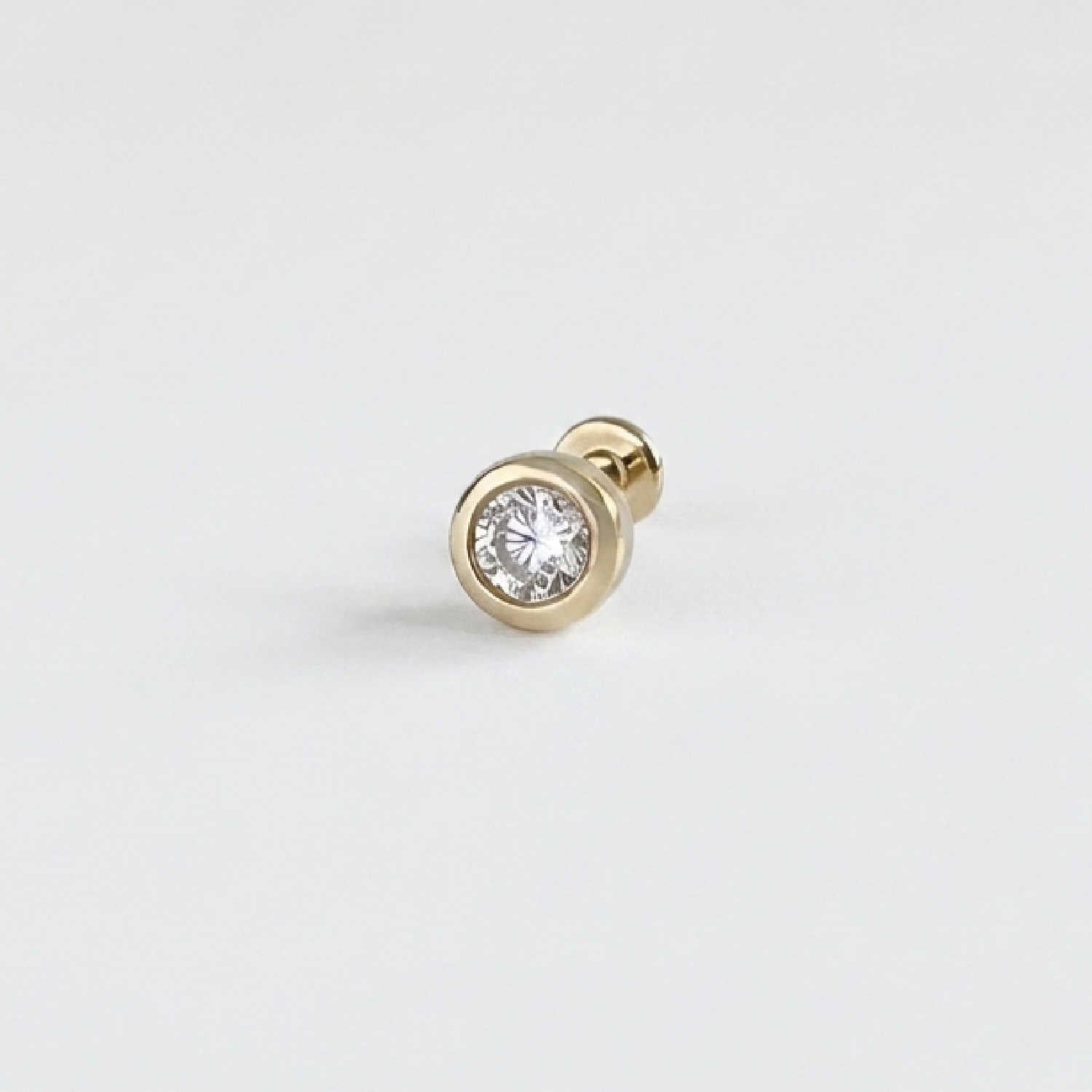 A single 14k solid gold stud flat back earring with a bezel-set diamond gemstone, shown on a clean, light gray background.