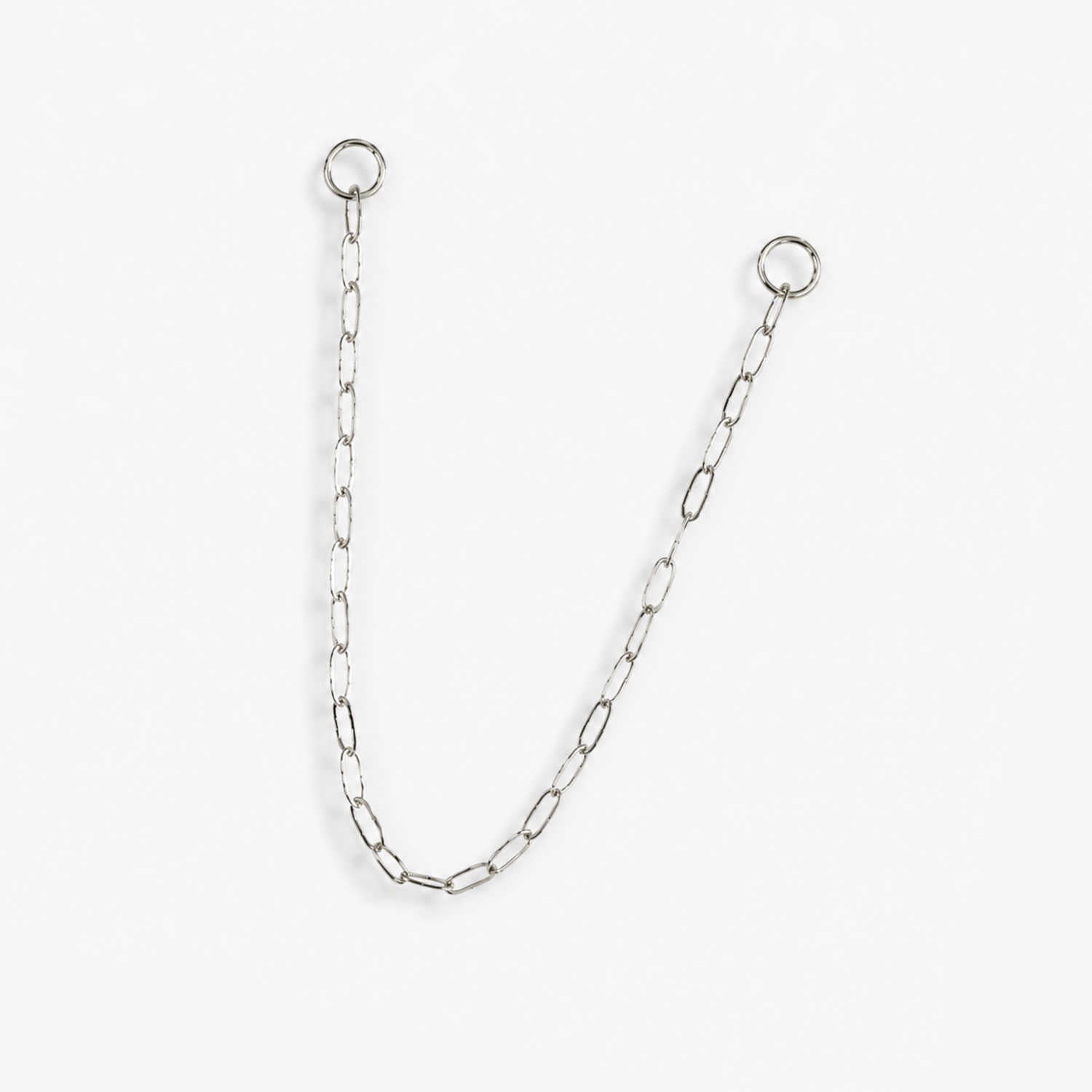 A delicate 14k white gold paperclip chain earring charm with two circular jump ring ends, displayed on a clean, light off-white background.