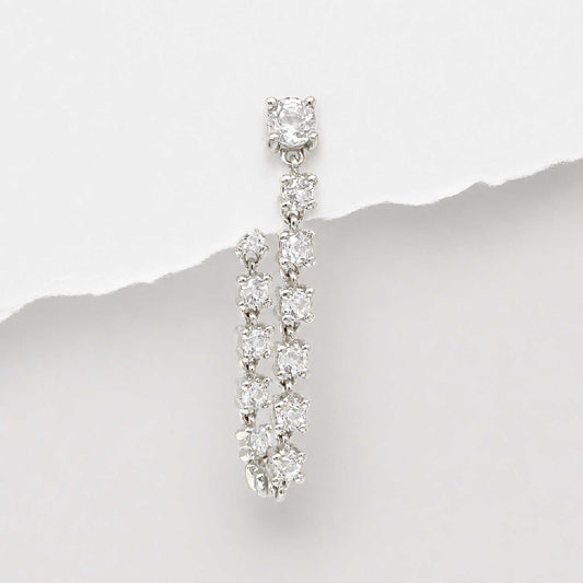 A 14k white gold flat back tennis style dangle earring with multiple round-cut diamonds, photographed against a white background with a torn-paper style divider.