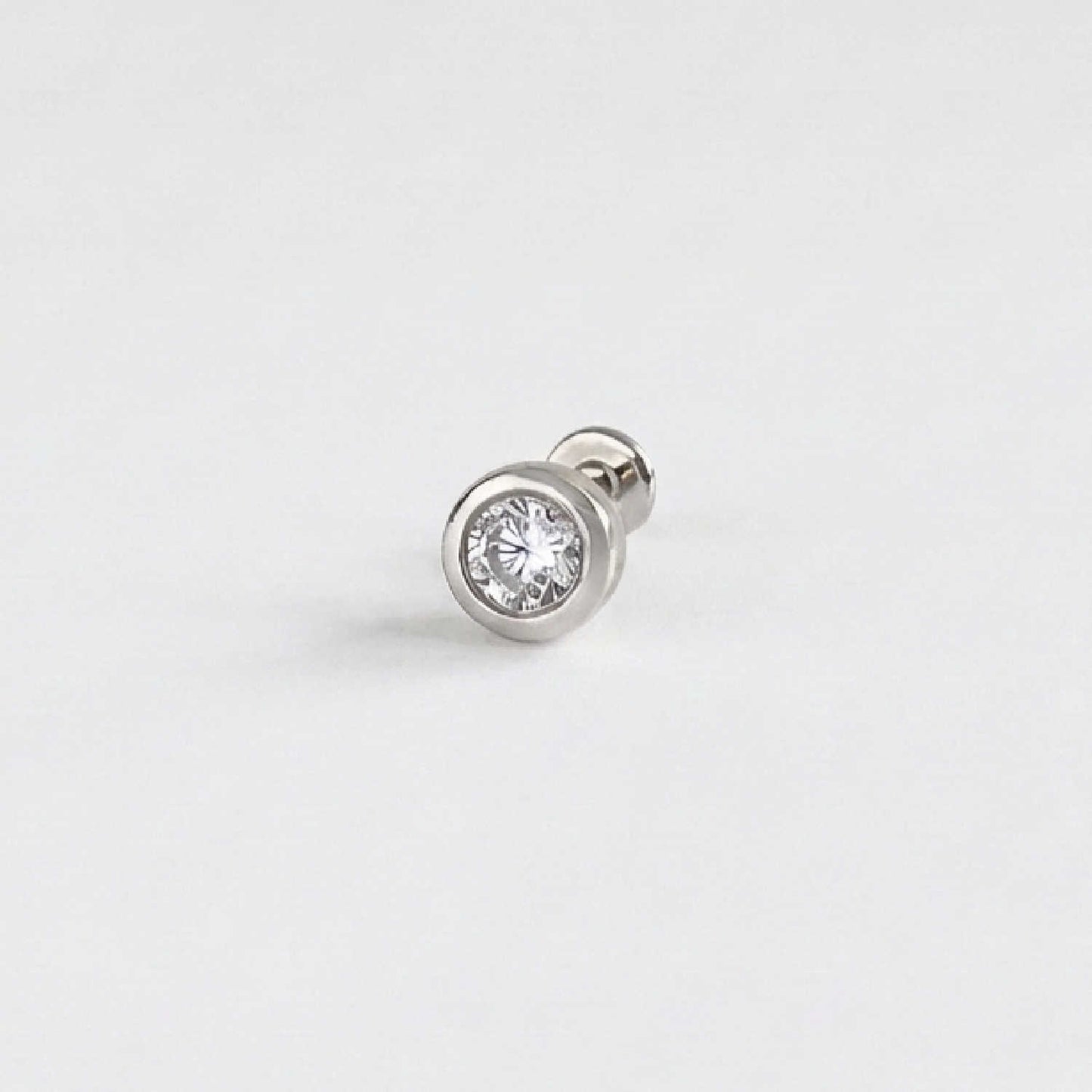 A single 14k solid white gold stud flat back earring with a bezel-set diamond gemstone, shown on a clean, light gray background.