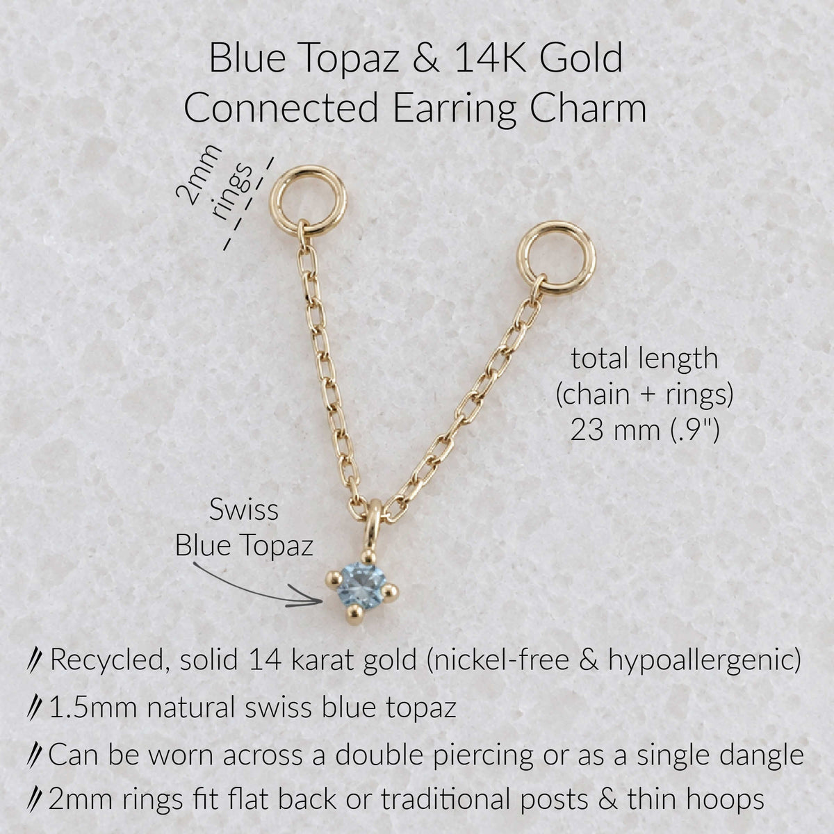 A gold earring charm with a blue topaz pendant on a textured light background, with text detailing its dimensions, materials, and wear options.