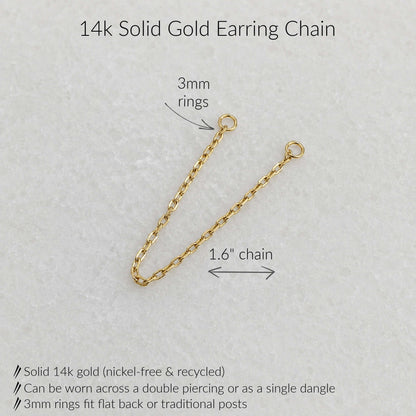 A 14k solid gold earring chain with two 3mm rings and a 1.6-inch chain length, shown on a light textured background with text labels and product details.