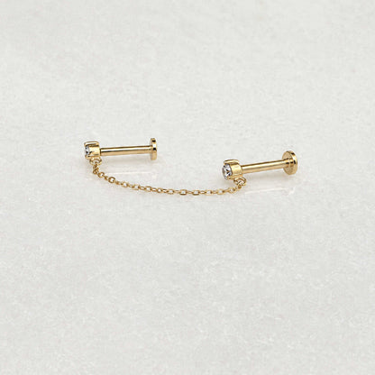 Side view of pair of 14k gold flat back earrings with a short chain connecting the diamond studs