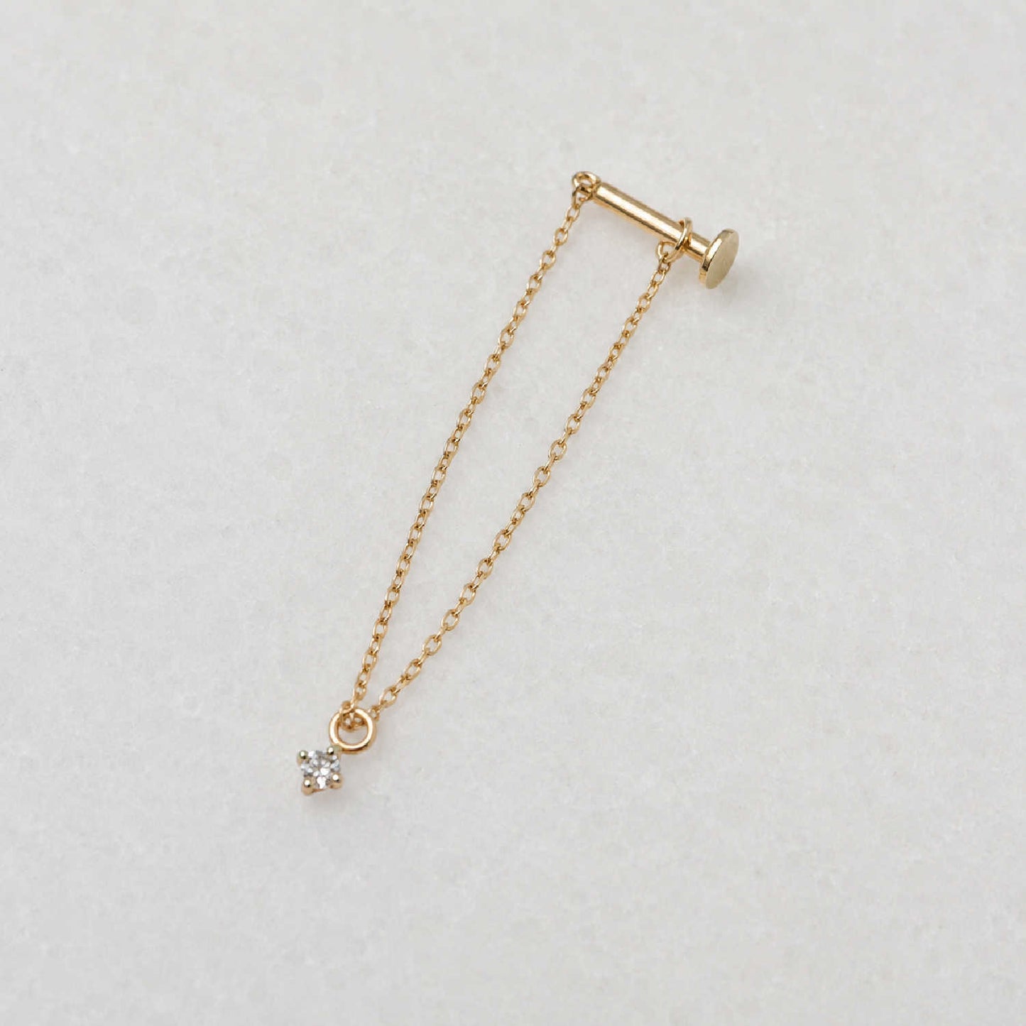 Side view of a long delicate 14k gold flat back chain earring with a floating diamond charm