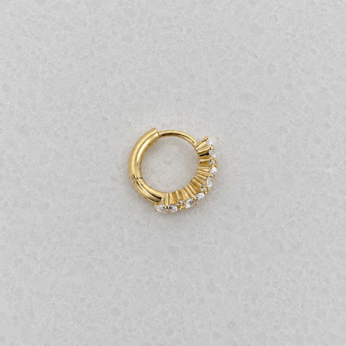 Side view of 14k gold plated huggie hoop earring with a vertical cluster of clear oval-cut and round stones