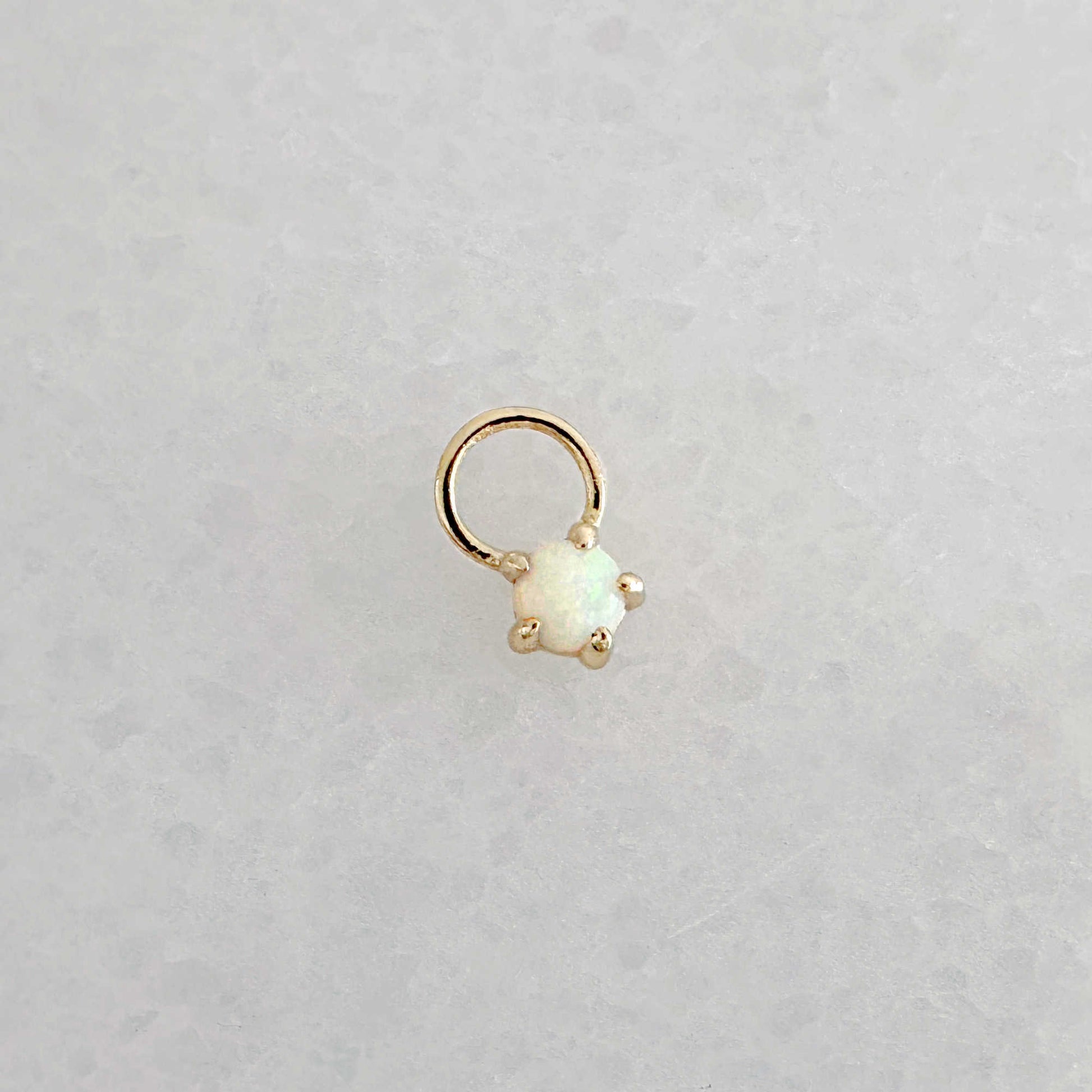 Gold hoop earring charm with a round opal gemstone