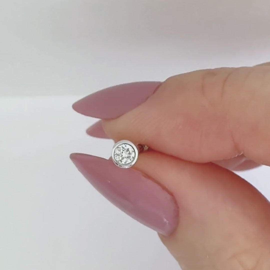 Video of a bezel set diamond stud earring in 14k white gold, showing the stud from all angles and operation of flat screw back labret post