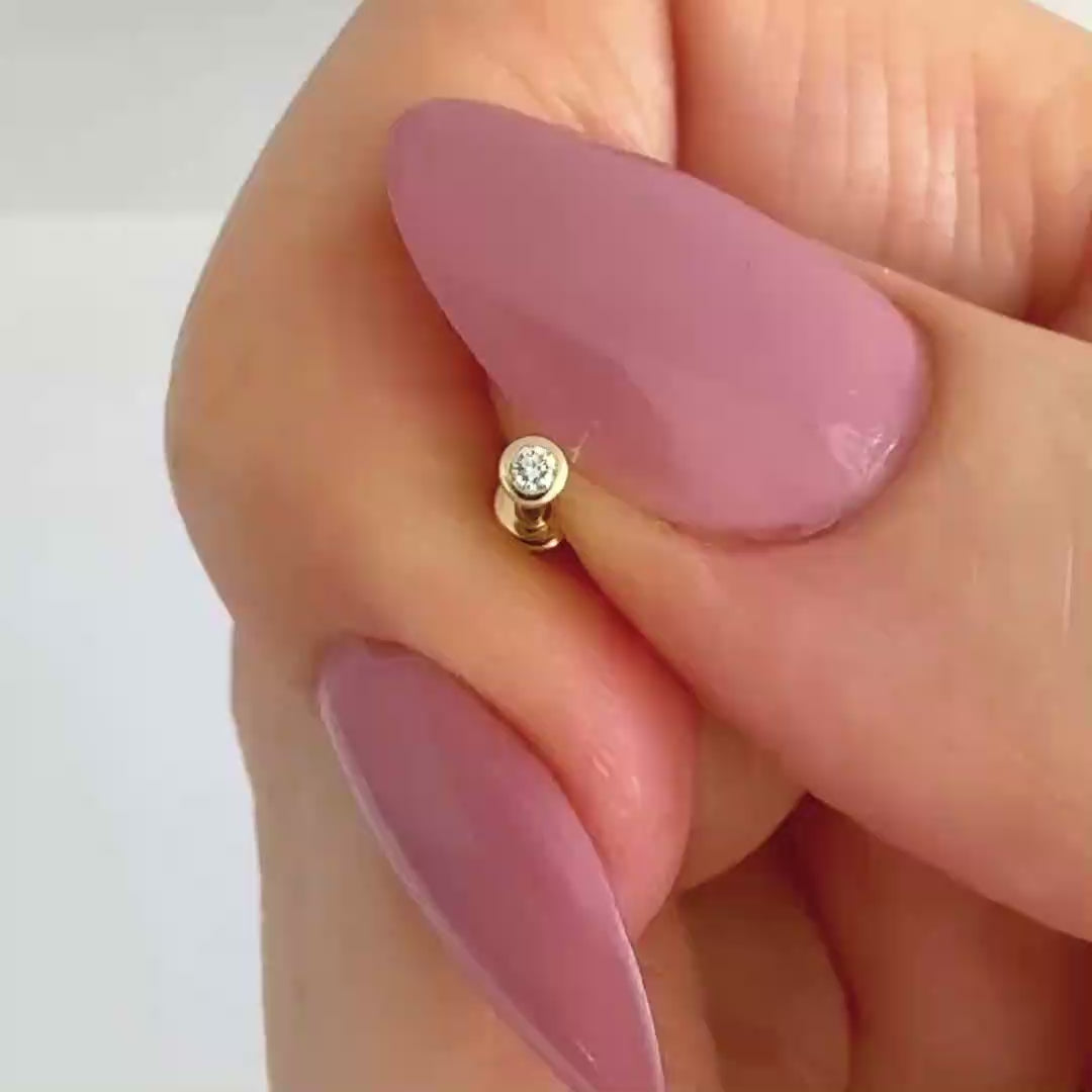 Video of a bezel set diamond stud earring in 14k yellow gold, showing the stud from all angles and operation of flat screw back labret post
