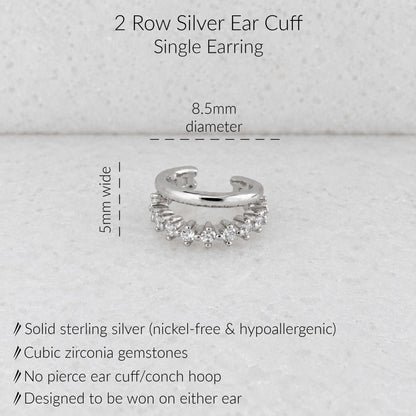 A silver open cuff earring with small clear gemstones, shown on a light textured background with text indicating dimensions: 8.5mm diameter and 5mm wide, plus product details about solid sterling silver and cubic zirconia gemstones.