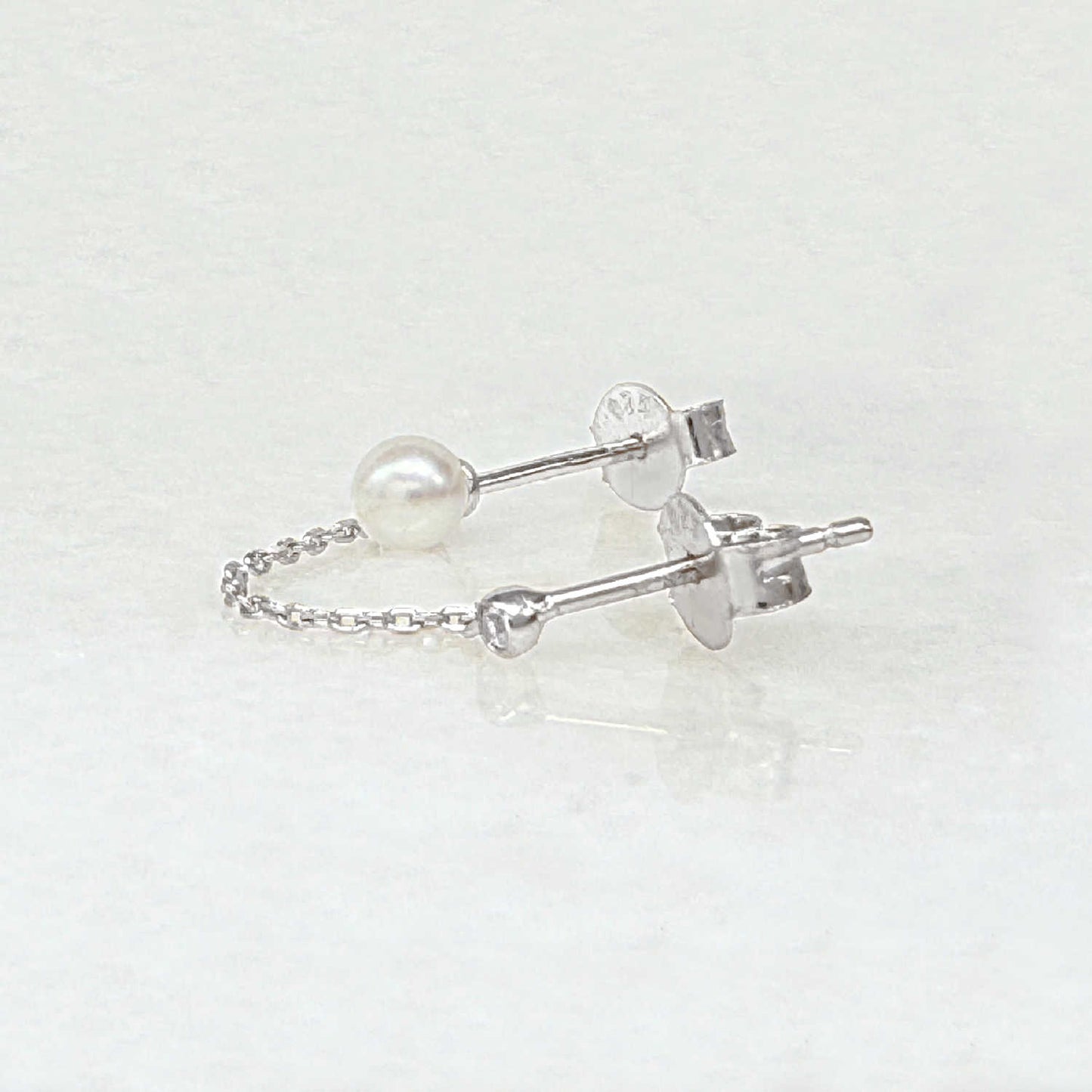Pearl double piercing stud earrings with sterling silver chains, side view