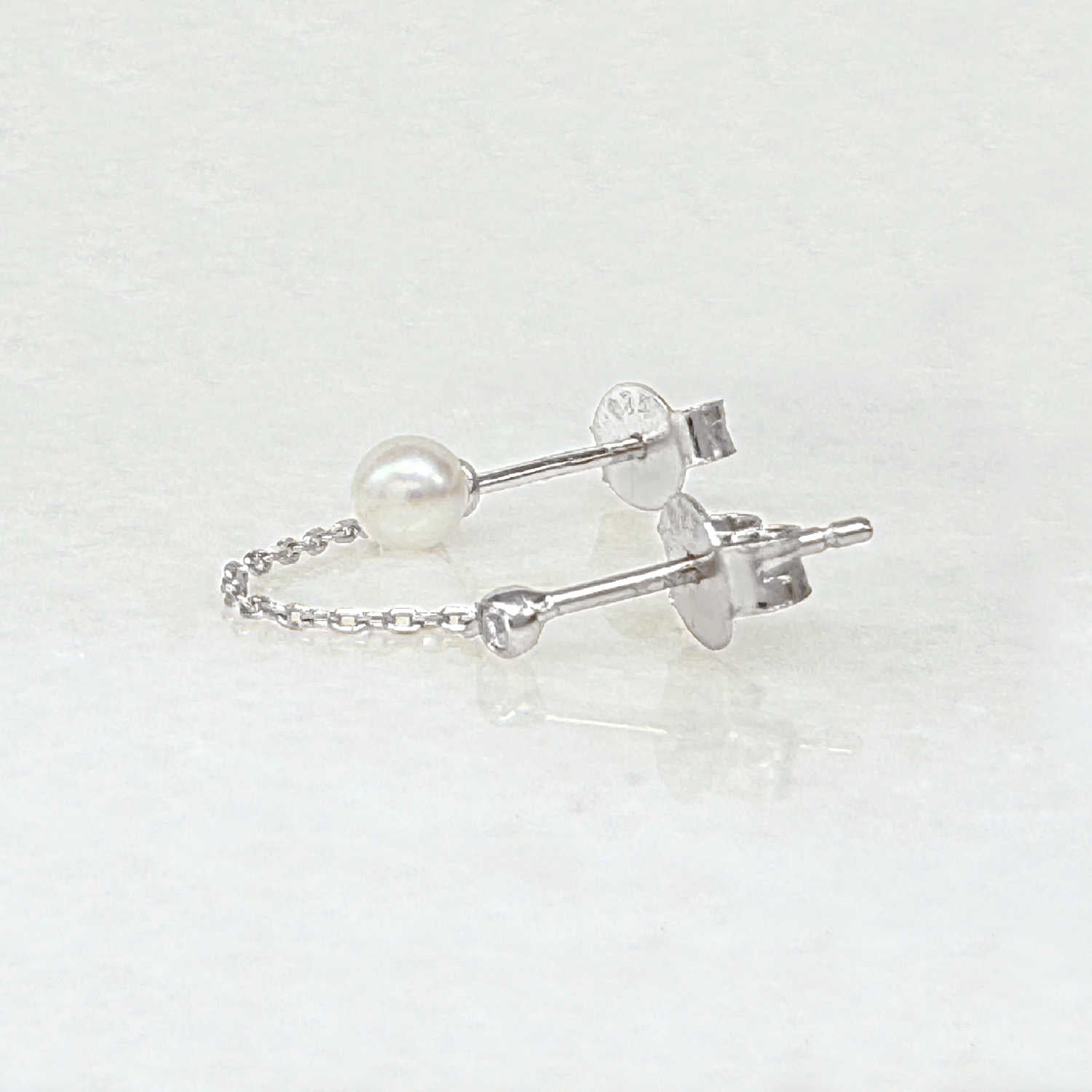 Pearl double piercing stud earrings with sterling silver chains, side view