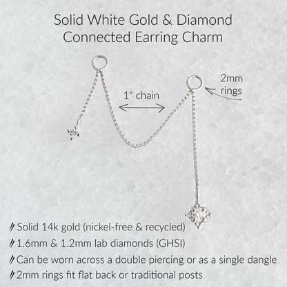 An informational product graphic for a solid white gold and diamond connected earring charm. The image shows a white gold chain with two circular rings, each holding a dangling diamond, with text labels indicating '1" chain', '2mm rings', and product details including 'Solid 14k gold (nickel-free & recycled)'